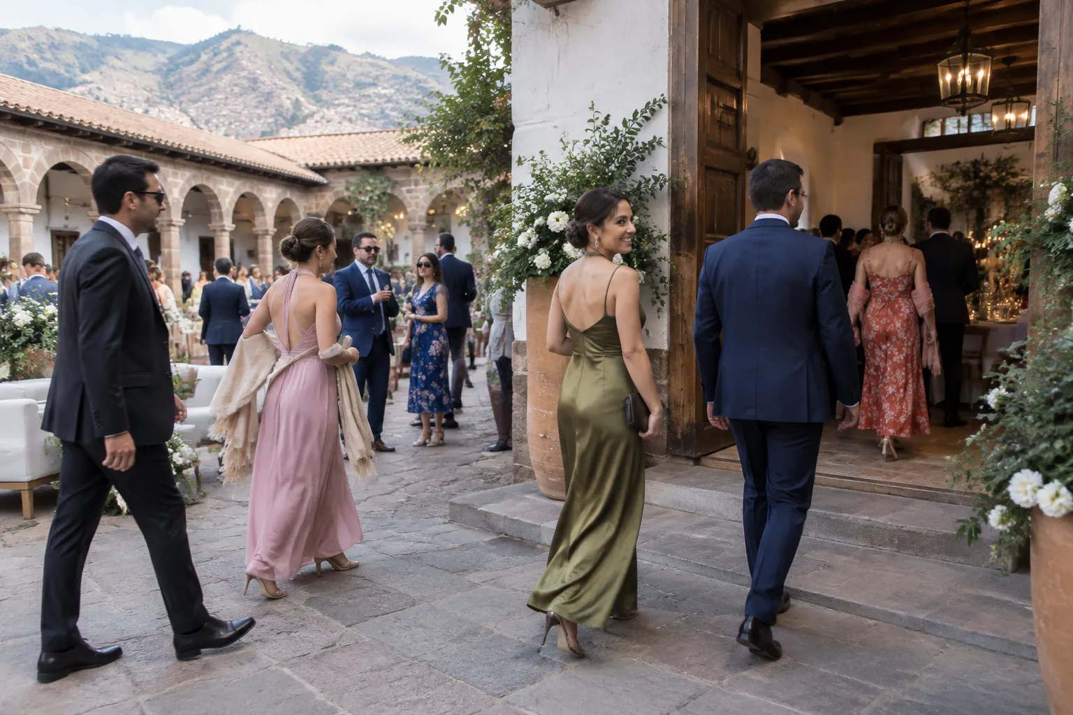 Wedding guests moving between an outdoor courtyard and indoor reception in layered formal clothing